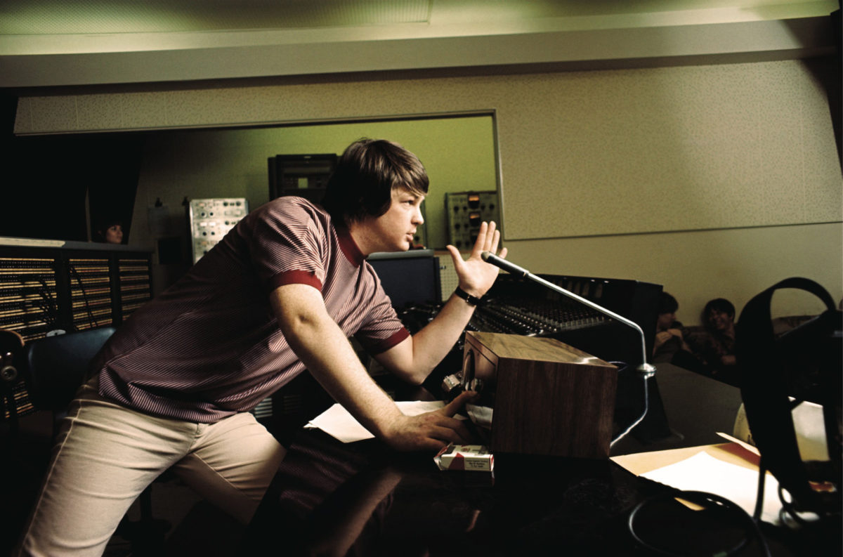 Brian Wilson leaning against studio console with hand up giving direction