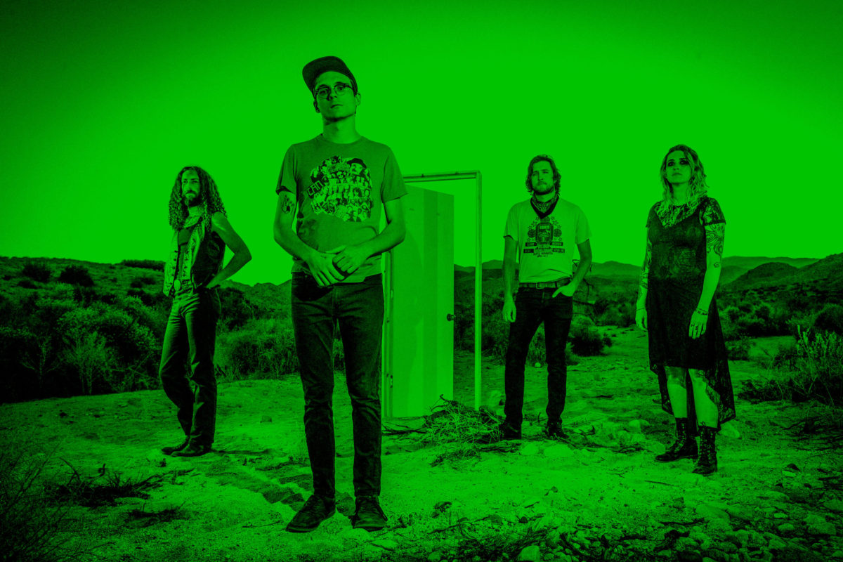 Photo of Frankie and the Witch Fingers standing on a plain with an open doorway and a green filter engulfing the entire image