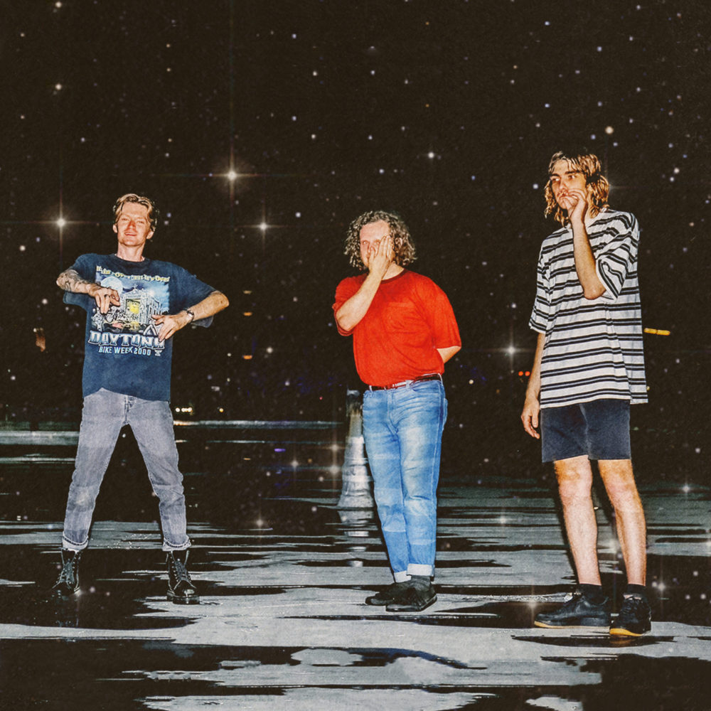 The three members of Acid Dad standing in front of space-like background