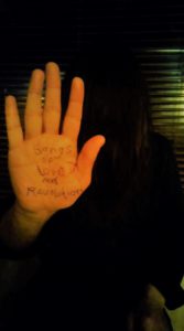 Hand pressed against window with Songs of Love and Revolution written on it.