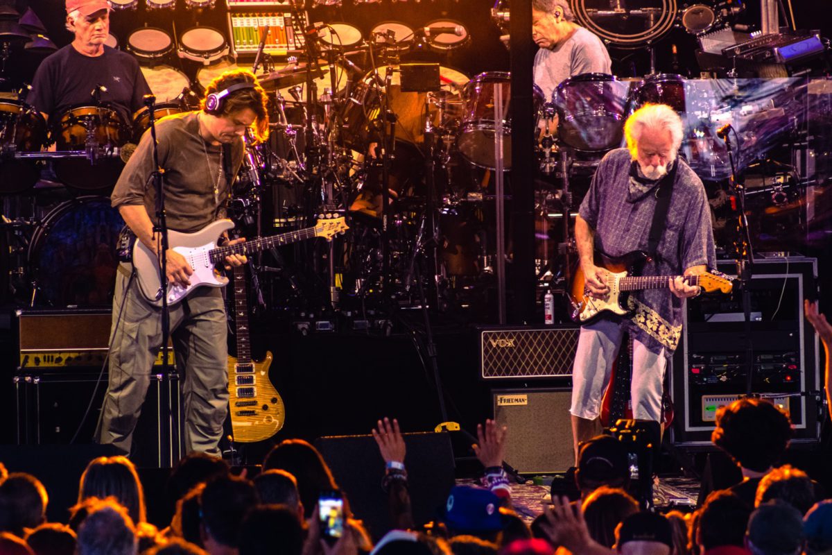 Dead & Company performing onstage with John Mayer on the left and Bob Weir on the right