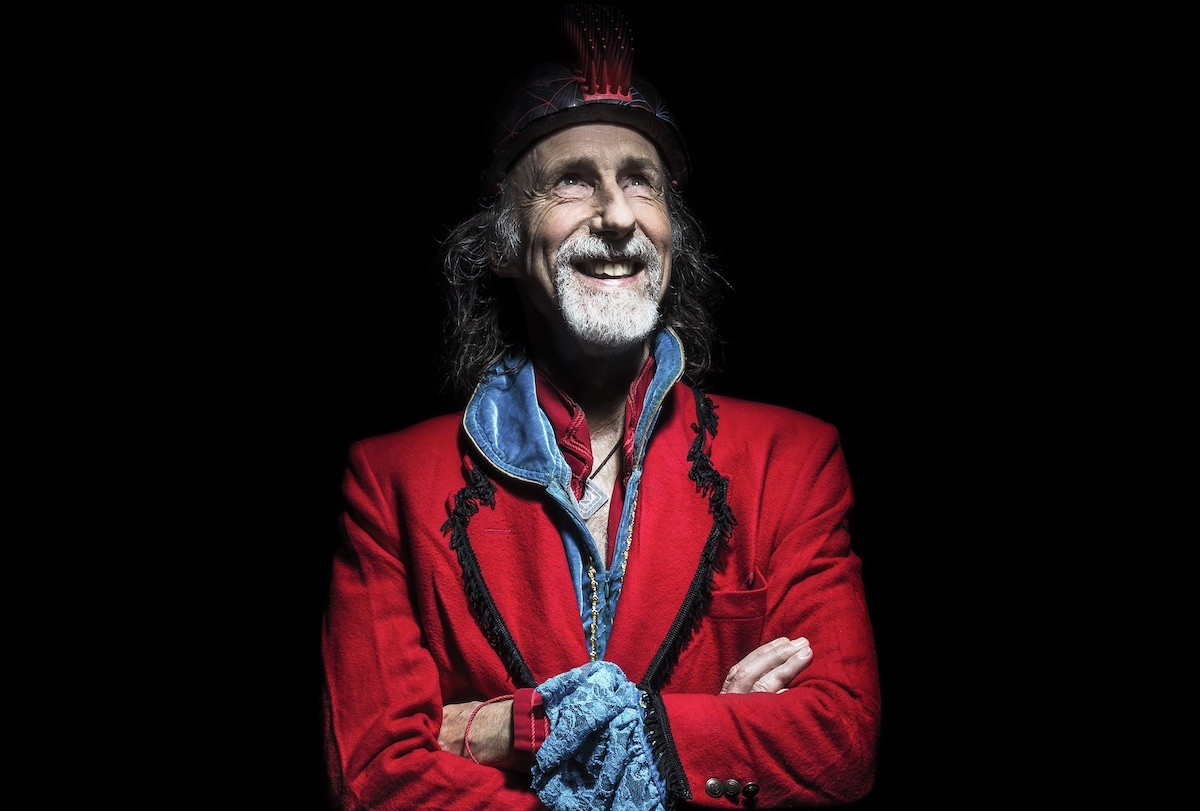 Arthur Brown in bright red jacket and blue shirt smiling with arms crossed