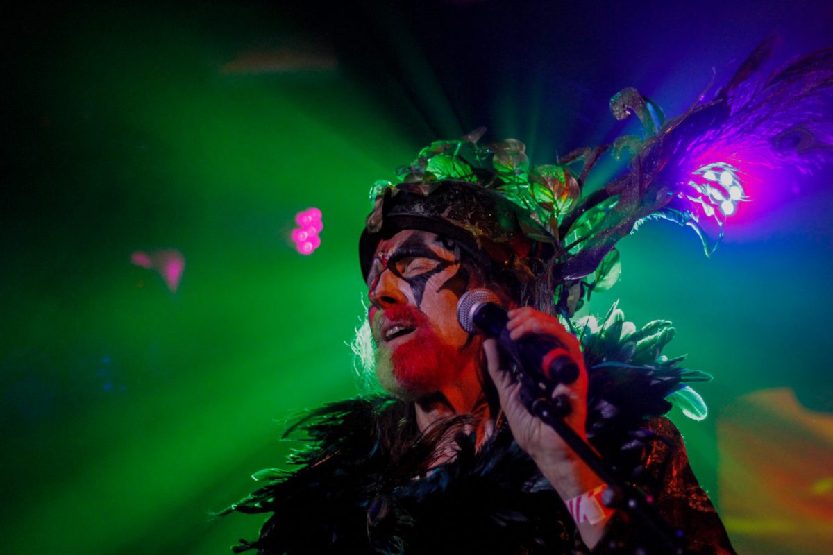 Arthur Brown performing live with intensely colorful lights behind him.