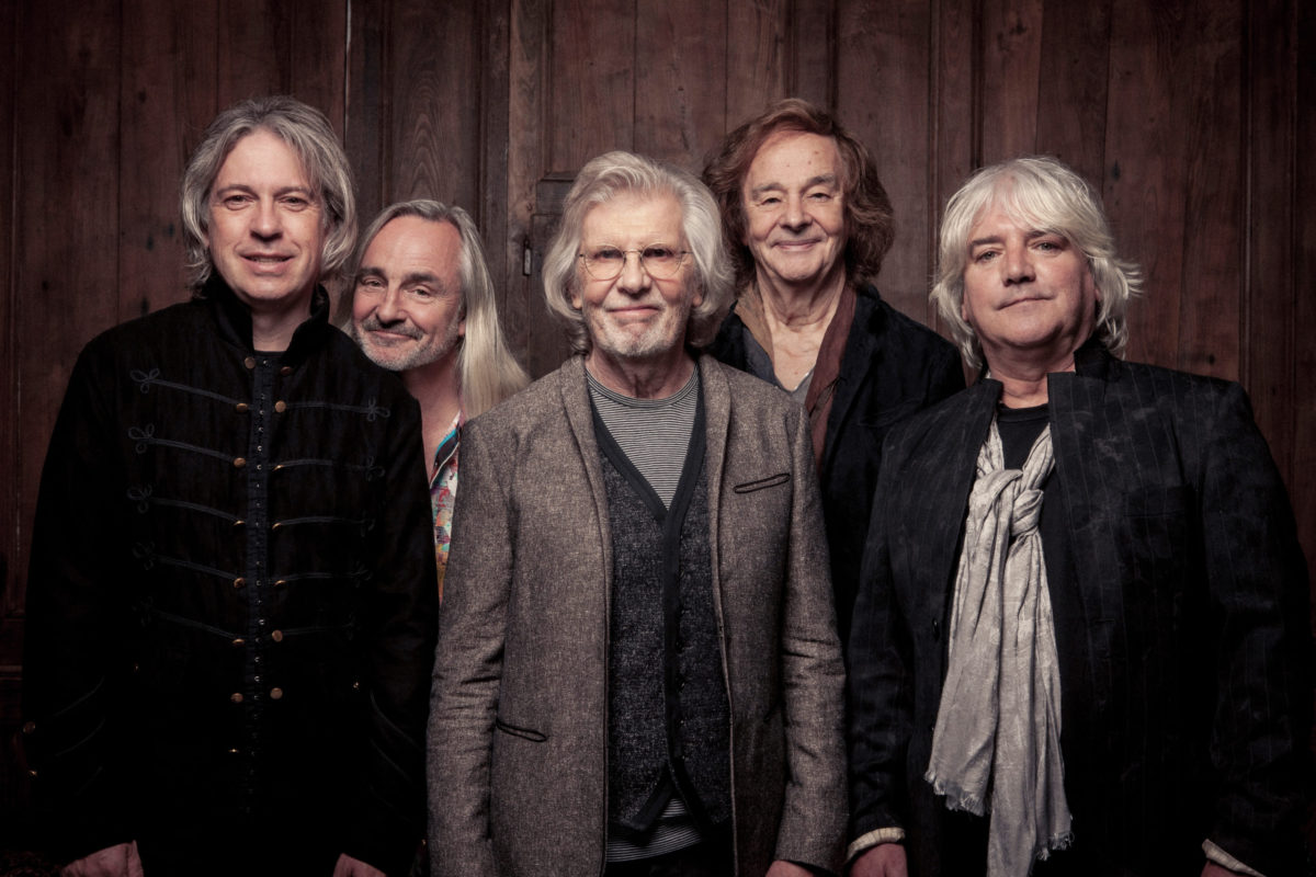All five members of The Zombies' current lineup standing in front of a brown curtain