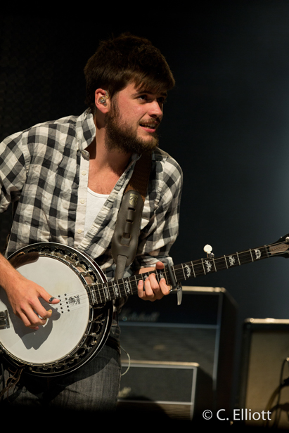 Young man in flannel shirt playing banjo and looking ahead expectantly