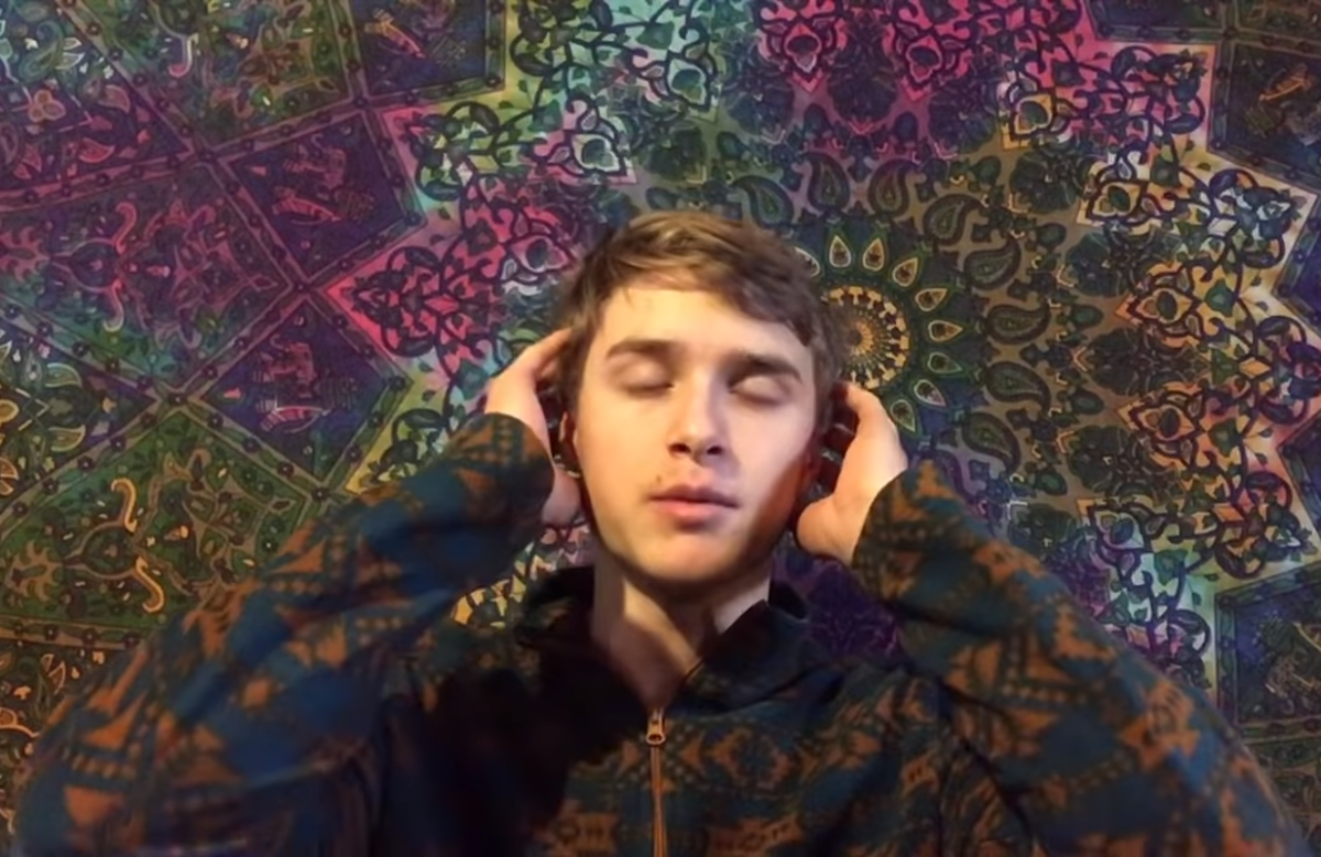 The author with eyes closed in psychedelic shirt in front of brightly colored tapestry