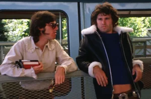 John Densmore and Jim Morrison hanging out together and leaning on a fence