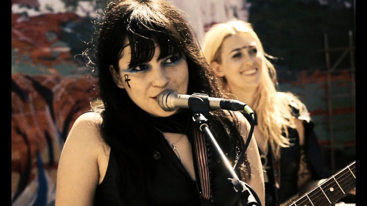 Bonnie Bloomgarden wearing sleeveless black top singing and playing guitar with Death Valley Girls at outdoor venue