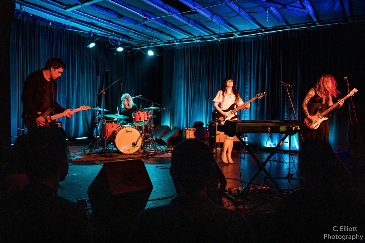 The four members of Death Valley Girls performing onstage indoors with blue lighting