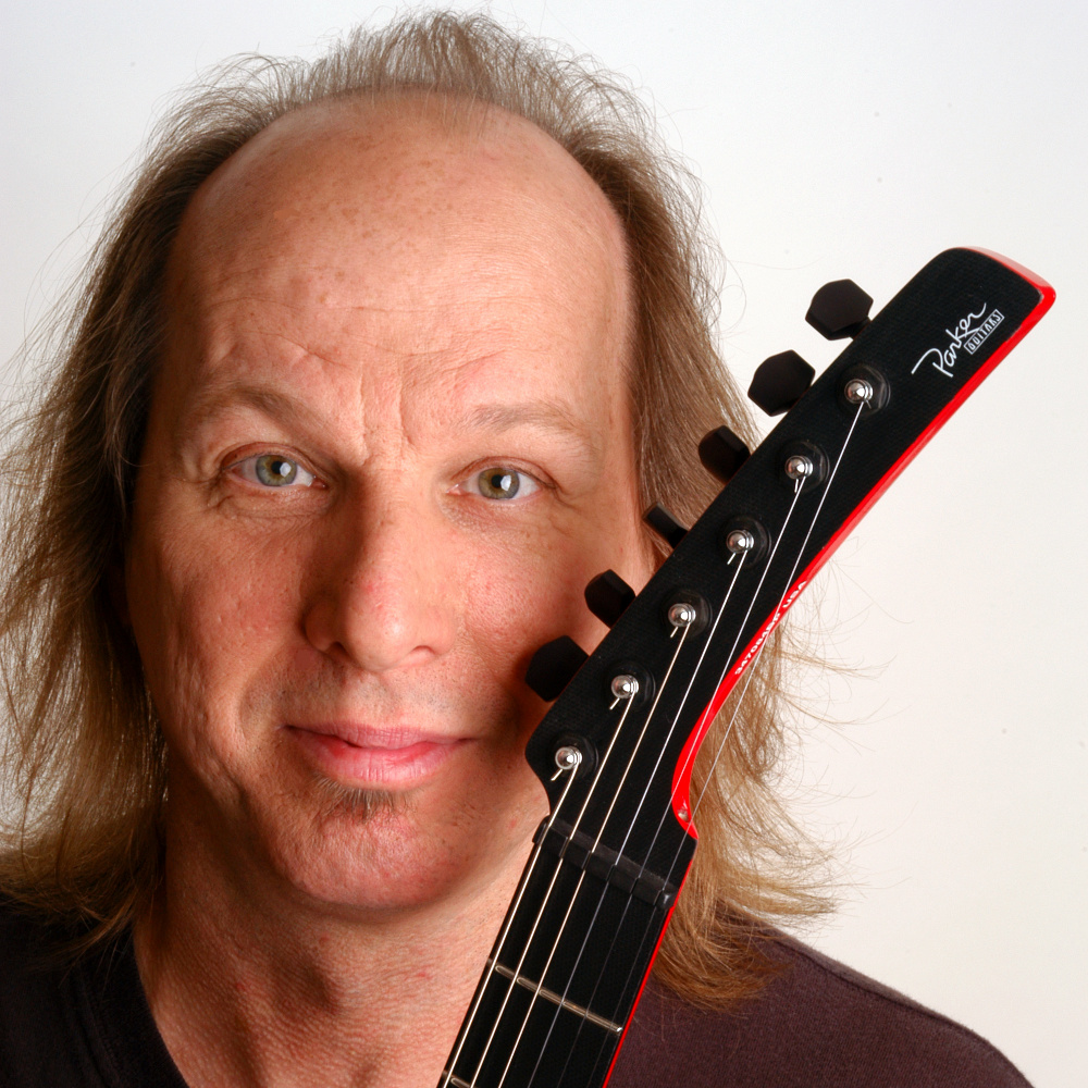 Close-up of Adrian Belew with guitar neck by face