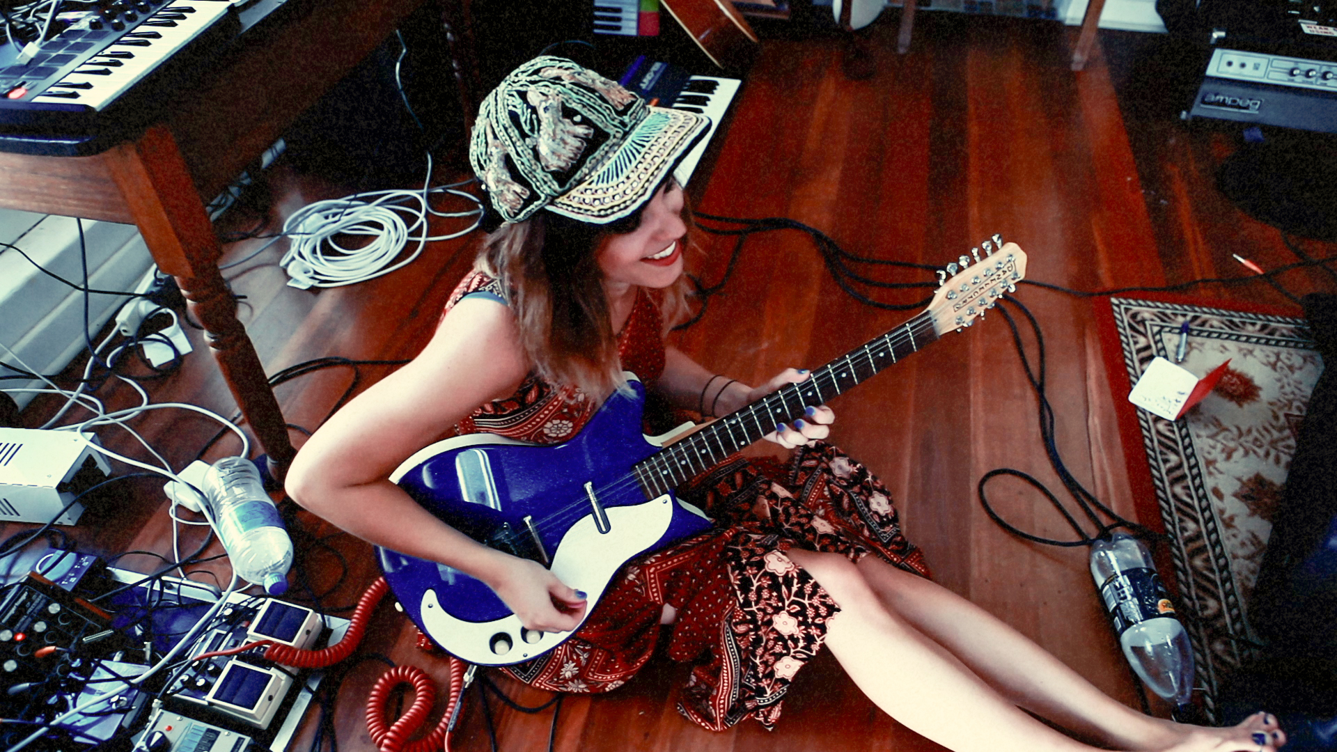 Melody Prochet sitting on floor of studio playing electric guitar