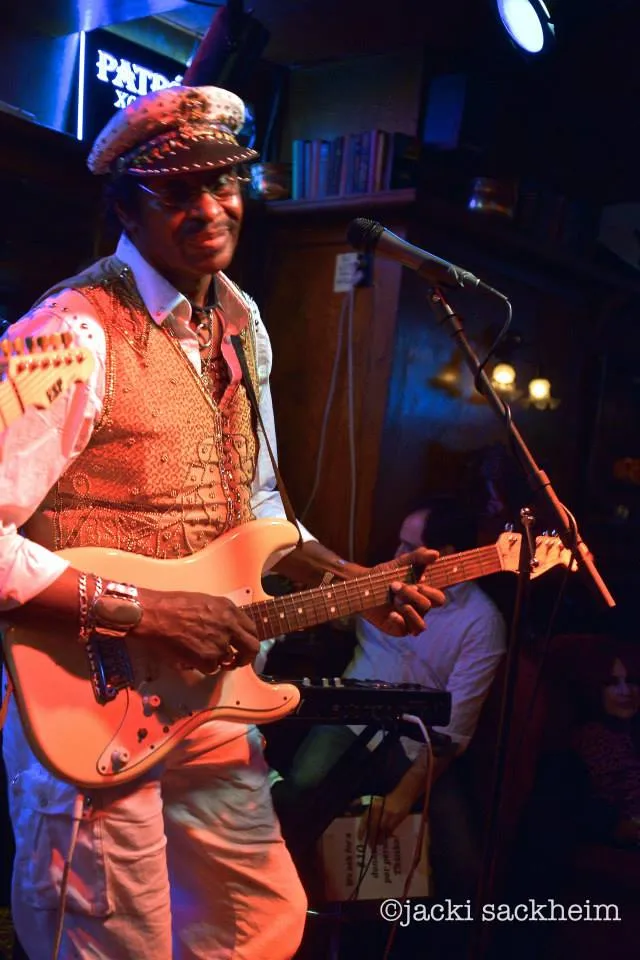 An older Willie Chambers playing guitar onstage at club