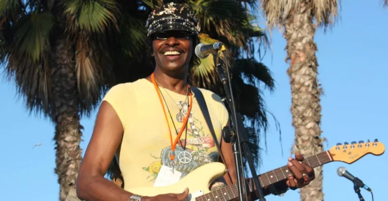 Willie Chambers posing with guitar in front of palm trees in Venice Beach