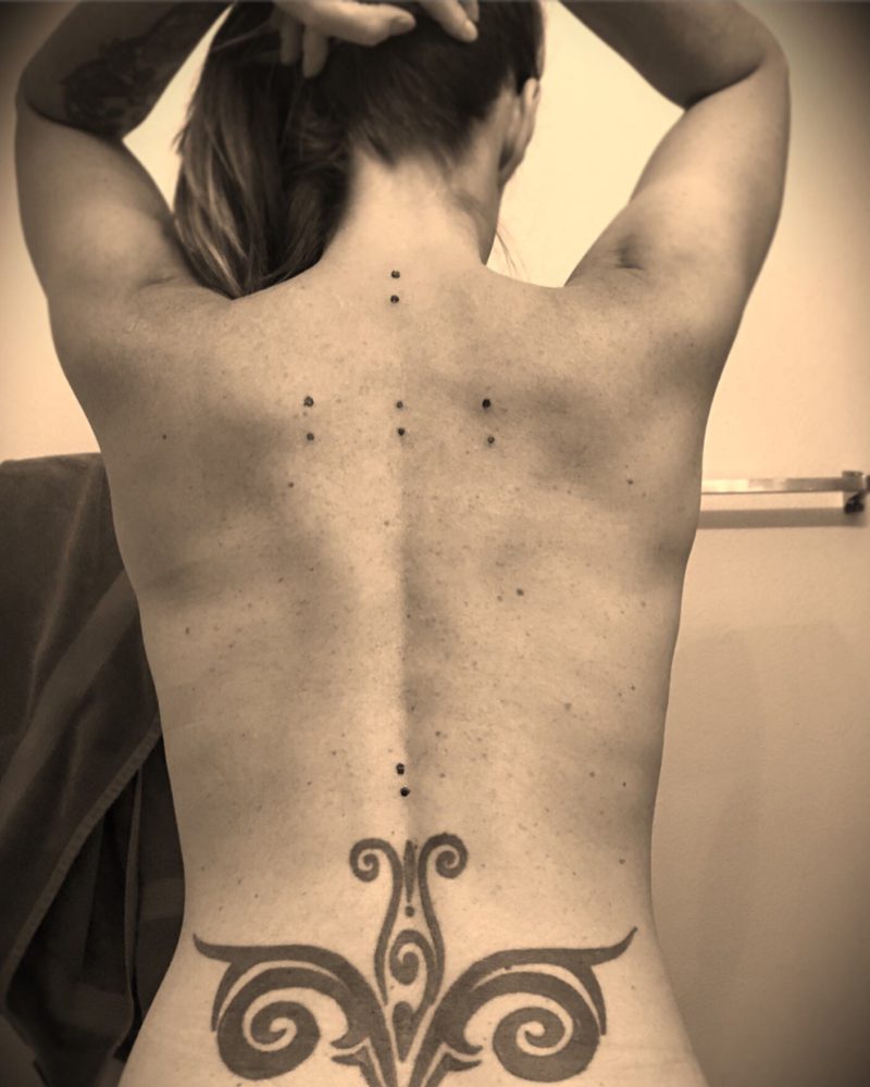 The author's naked backside with kambo holes and large floral tattoo on lower back
