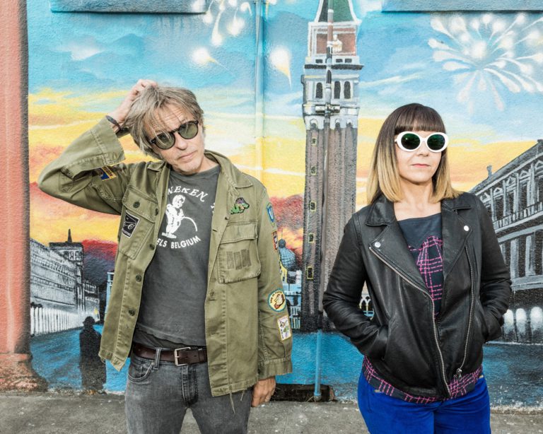 Sam Coomes and Janet Weiss of Quasi standing in front of a mural.