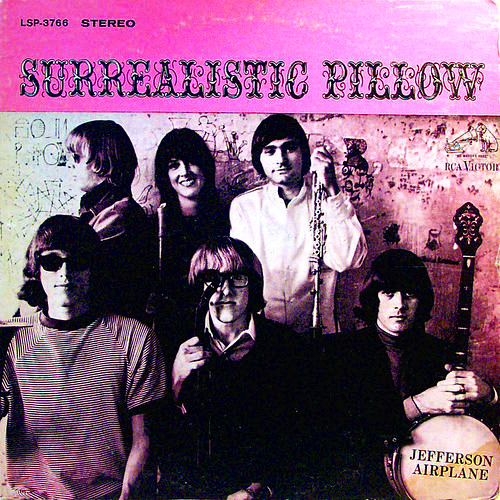 The six members of Jefferson Airplane standing or sitting in front of a wall with their instruments with a pink heading at the top that lists the name of the album.