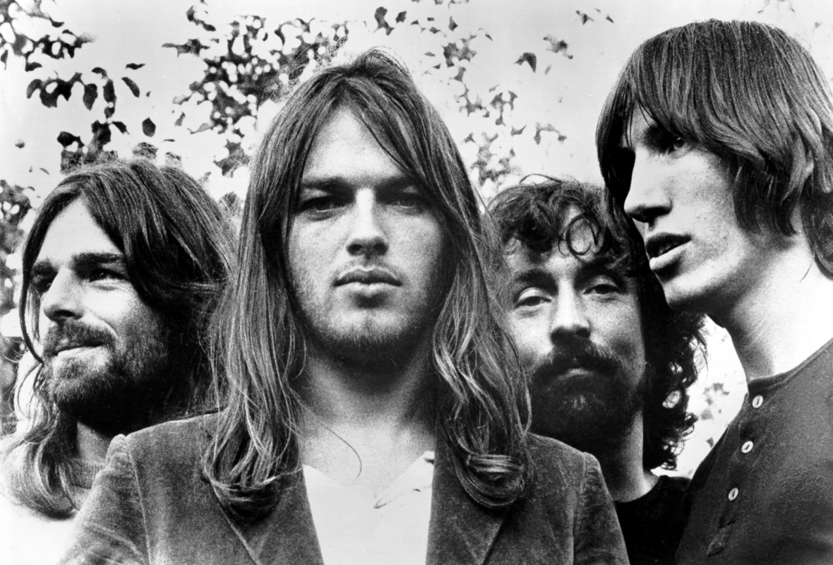 Black and white close-up of Pink Floyd band members in 1973 with David Gilmour in the foreground staring into camera