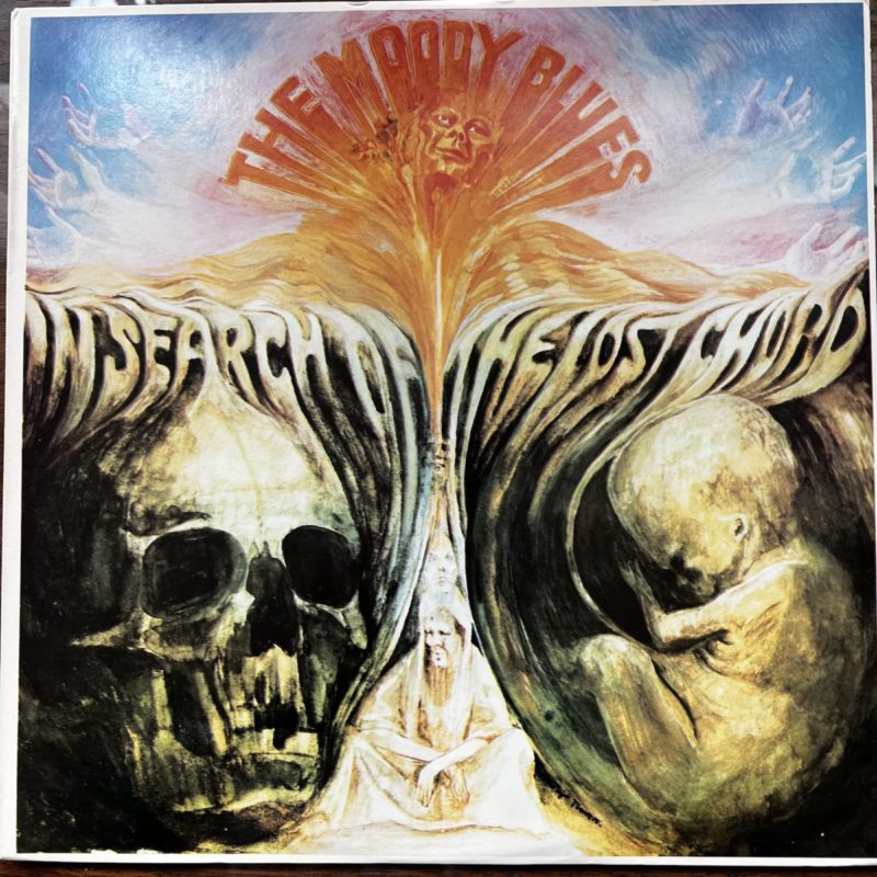 Images of human skull and human fetus with "In Search of the Lost Chord" engraved above and "The Moody Blues" in a red arc over a human figure