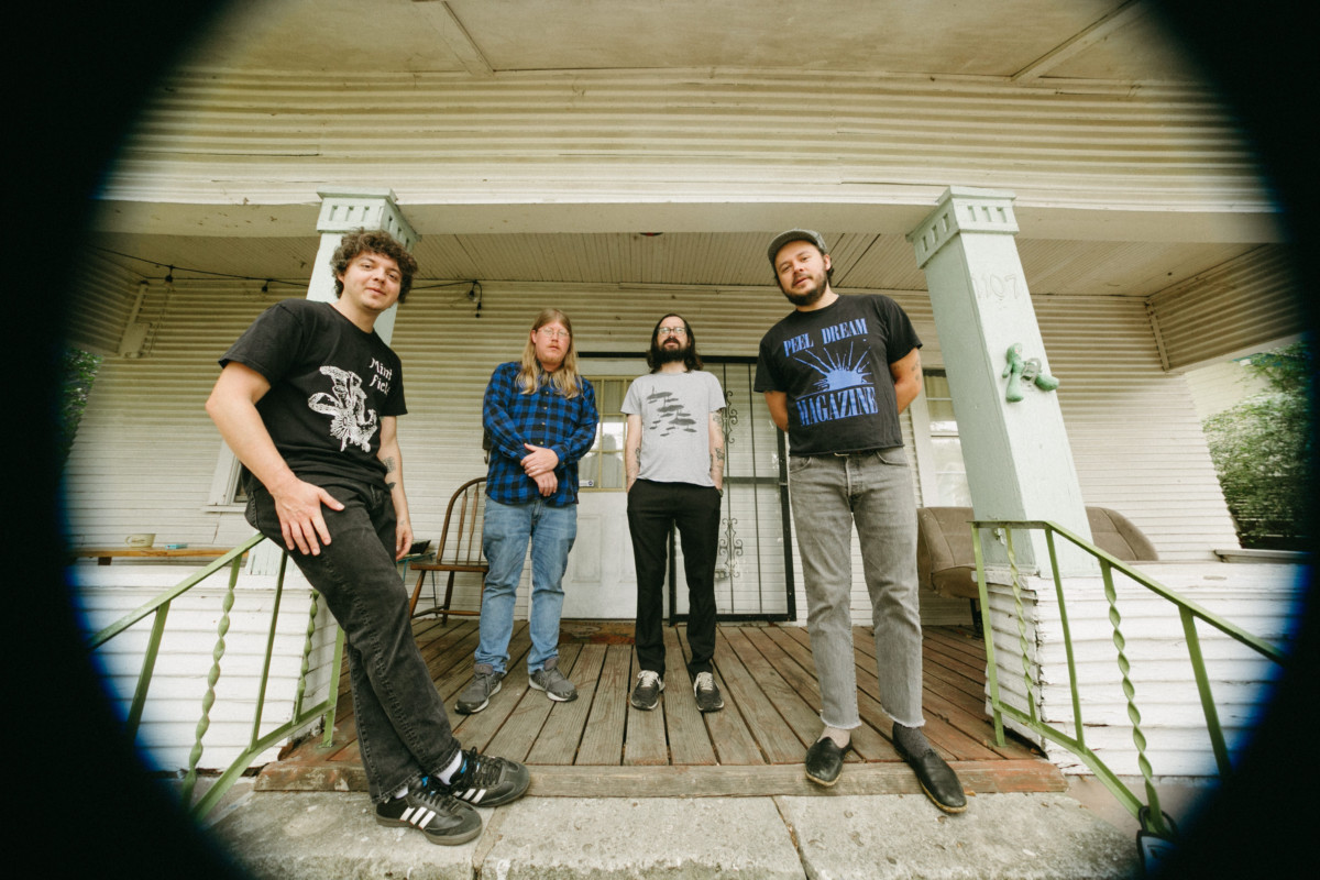 The four members of Holy Wave standing on a stairwell looking at the camera, which has a vignette effect in place.