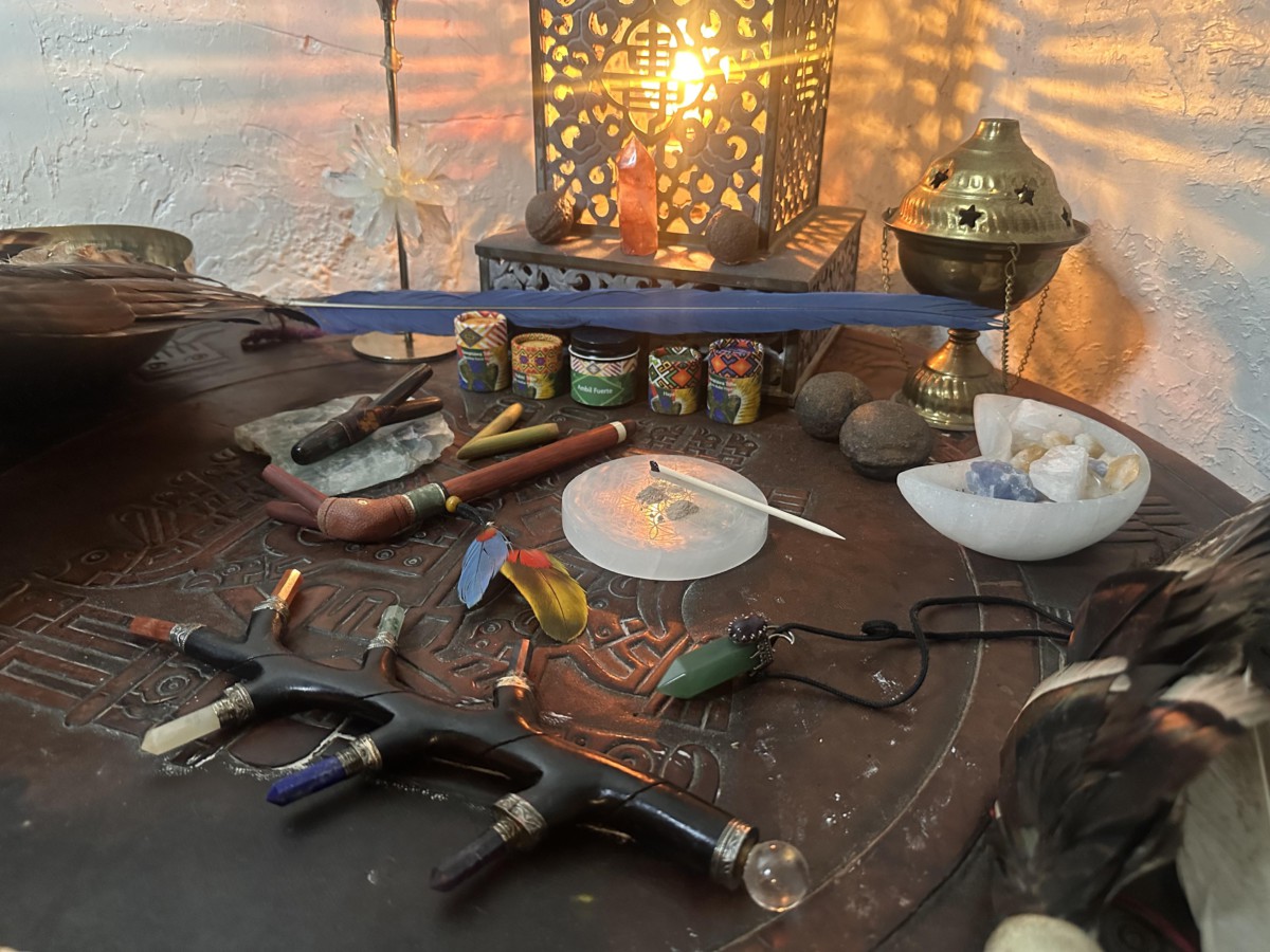 Image of a circular dark brown wooden table with various items laid out, including a pipe used for blowing hape and a white platelet with an off-white powder on it.