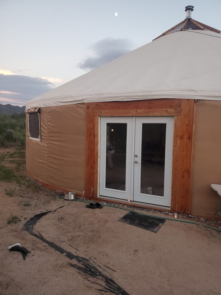 Photo of the outside of the ceremonial space--a yurt with built-in double-doors set in the desert