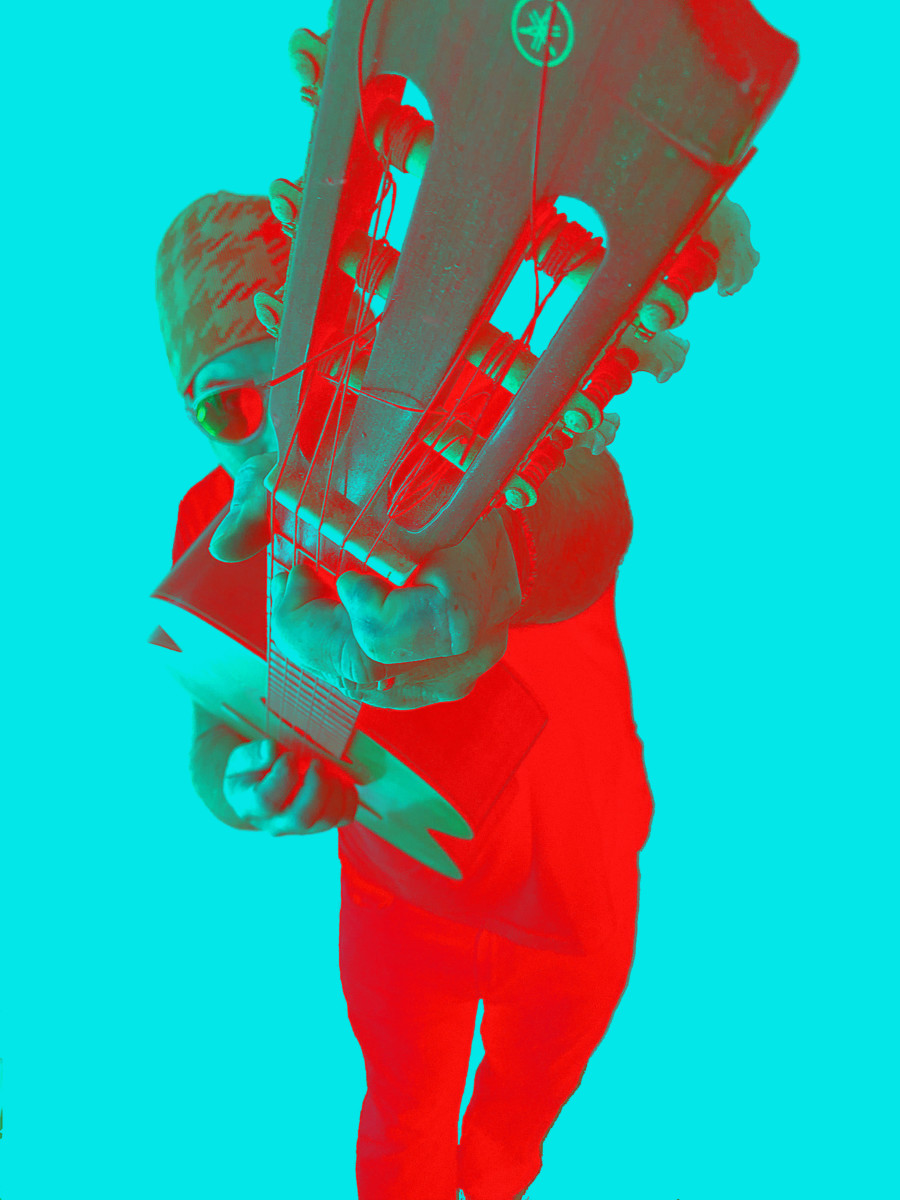 Negative, color-enhanced photo of man holding guitar toward camera