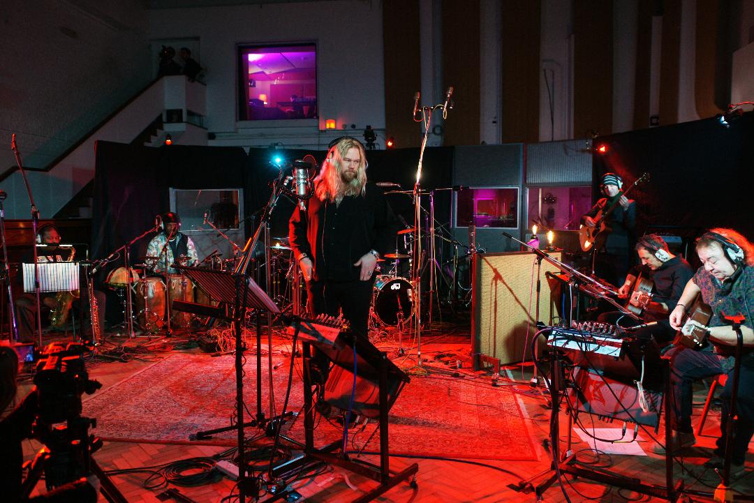 Musicians rehearsing and/or recording in large studio with red carpet