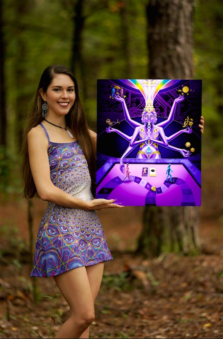 The artist Juliana Garces, wearing a colorful mini-dress, holding up one of her vibrant works of art in a forest