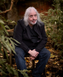 Nick Saloman sitting on a log among trees