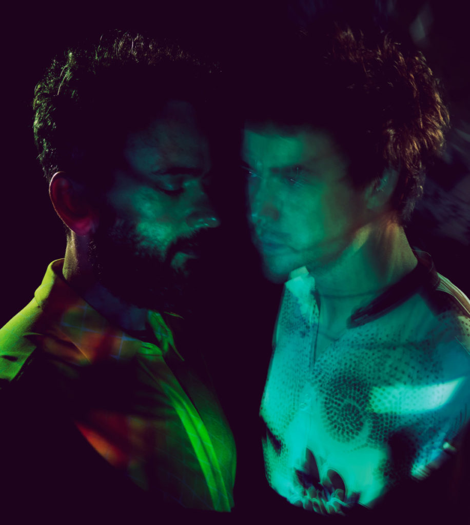 Shadowy photo of the two members of MGMT with colored lights strategically placed on them.