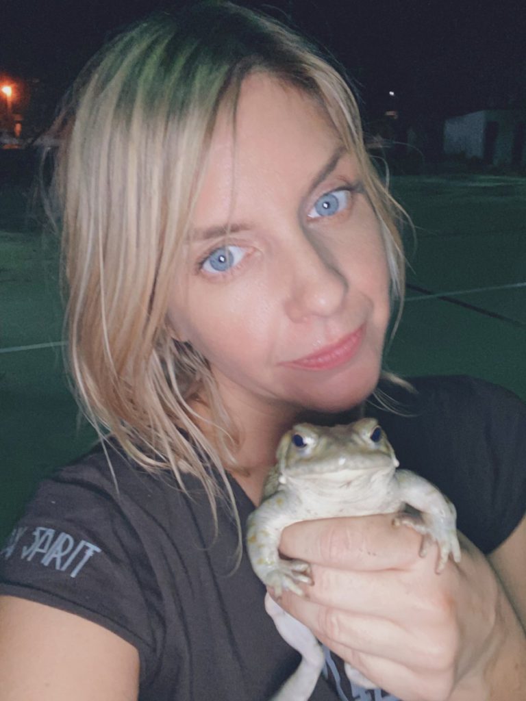 Close-up of a young blonde woman holding a toad in her hands