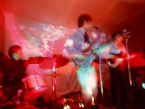 Pink Floyd performing onstage in 1966 with psychedelic lighting