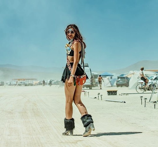 Photo of the author in burner garb turning around to face the camera in the dusty environs of Burning Man