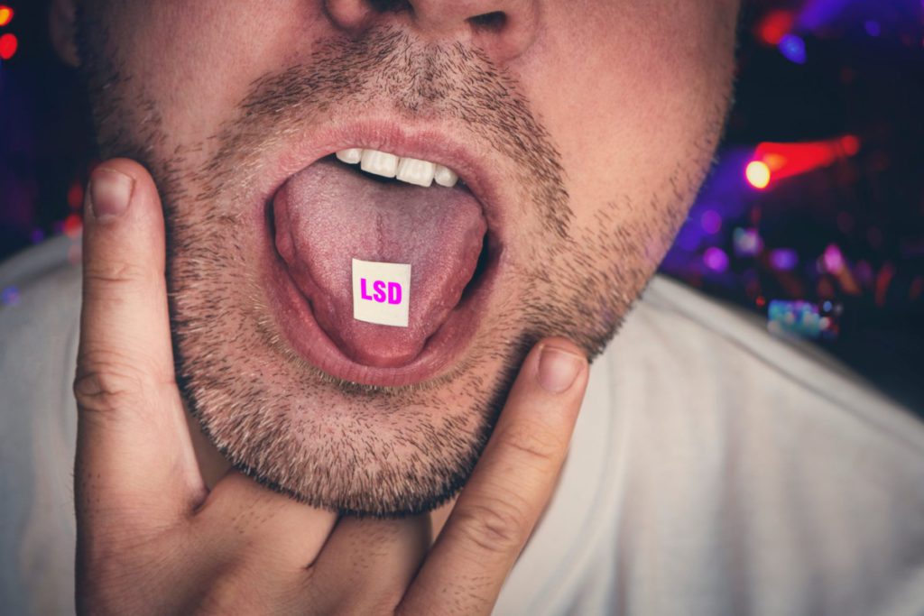 White man sticking out tongue with tab of LSD on it