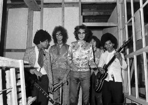 Black and white photo of five men, some holding instruments.