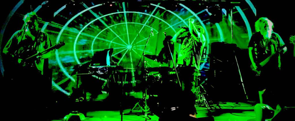 Photo of a band performing onstage with green lighting