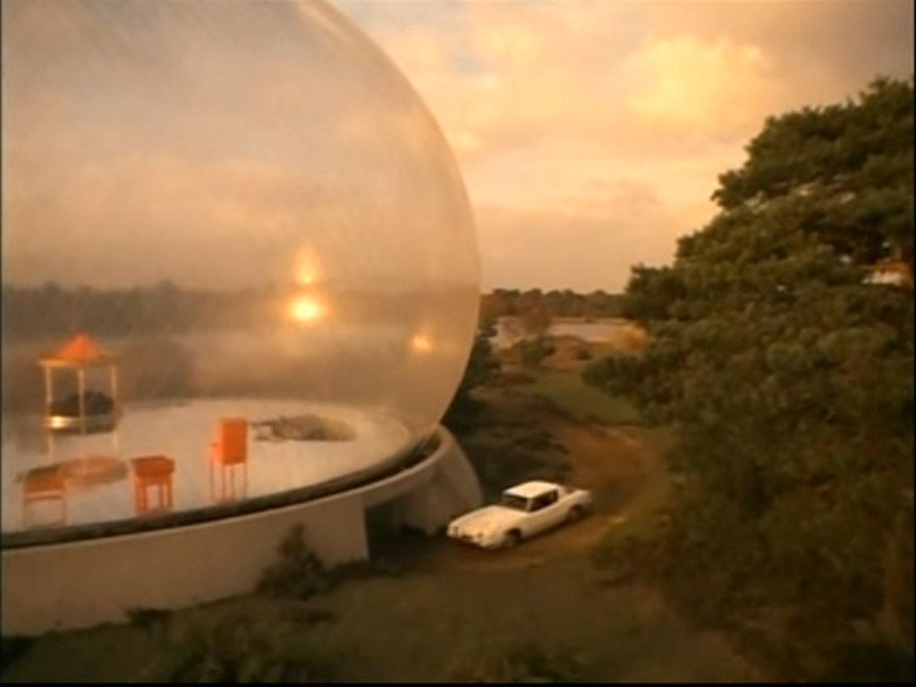 A surreal image of a giant inhabited bubble with a white car parked next to it and trees near it.