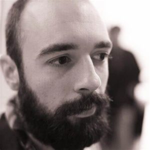 Close-up of young white man's face. The man is bearded and balding.
