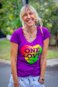 Blonde middle-age woman in pink shirt with multi-colored heart on it.
