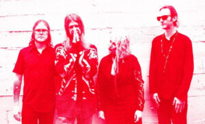 Iridescent red image of the four members of Morrison Graves standing in front of a wall