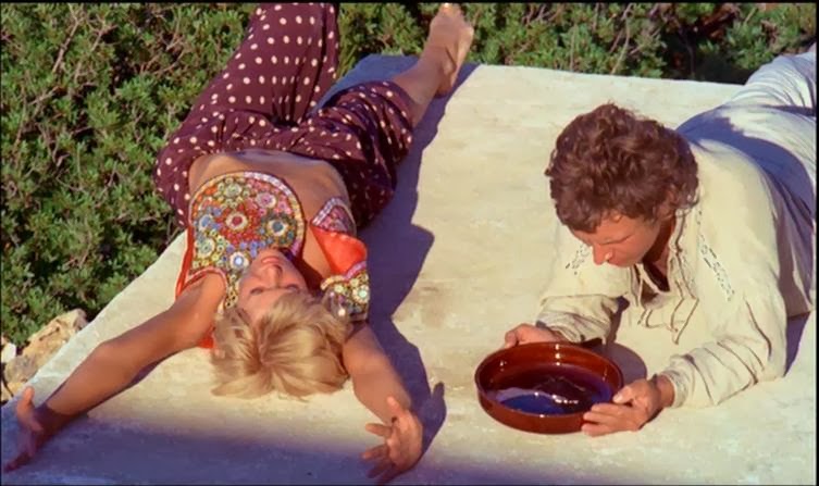 Image of a young hippie man and hippie woman together on a blanket on grass