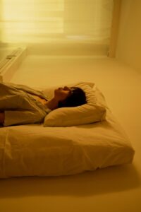 Woman lying on bed in therapeutic setting with curtains drawn
