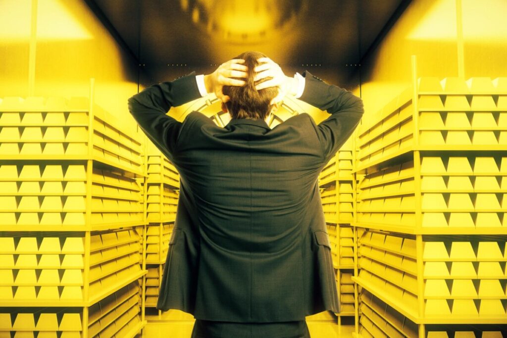 Man in suit Inside Gold Vault with hands on back of head