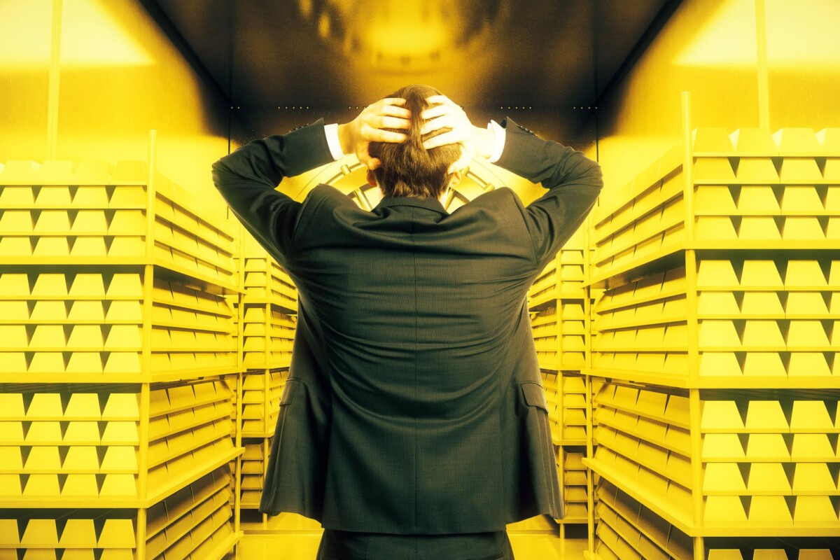 Man in suit Inside Gold Vault with hands on back of head