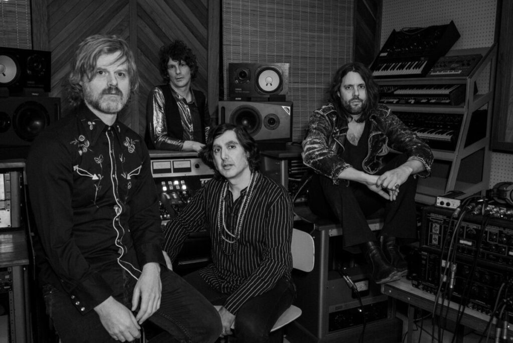 Black and white photo of the members of the band Elephant Stone sitting in a studio looking at the camera