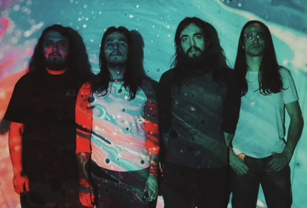 The four long-haired members of Peaceful Retreat with a psychedelic projection on them.