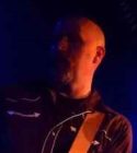 Bald white man in dark with light on left side of face