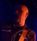 Bald white man in dark with light on left side of face